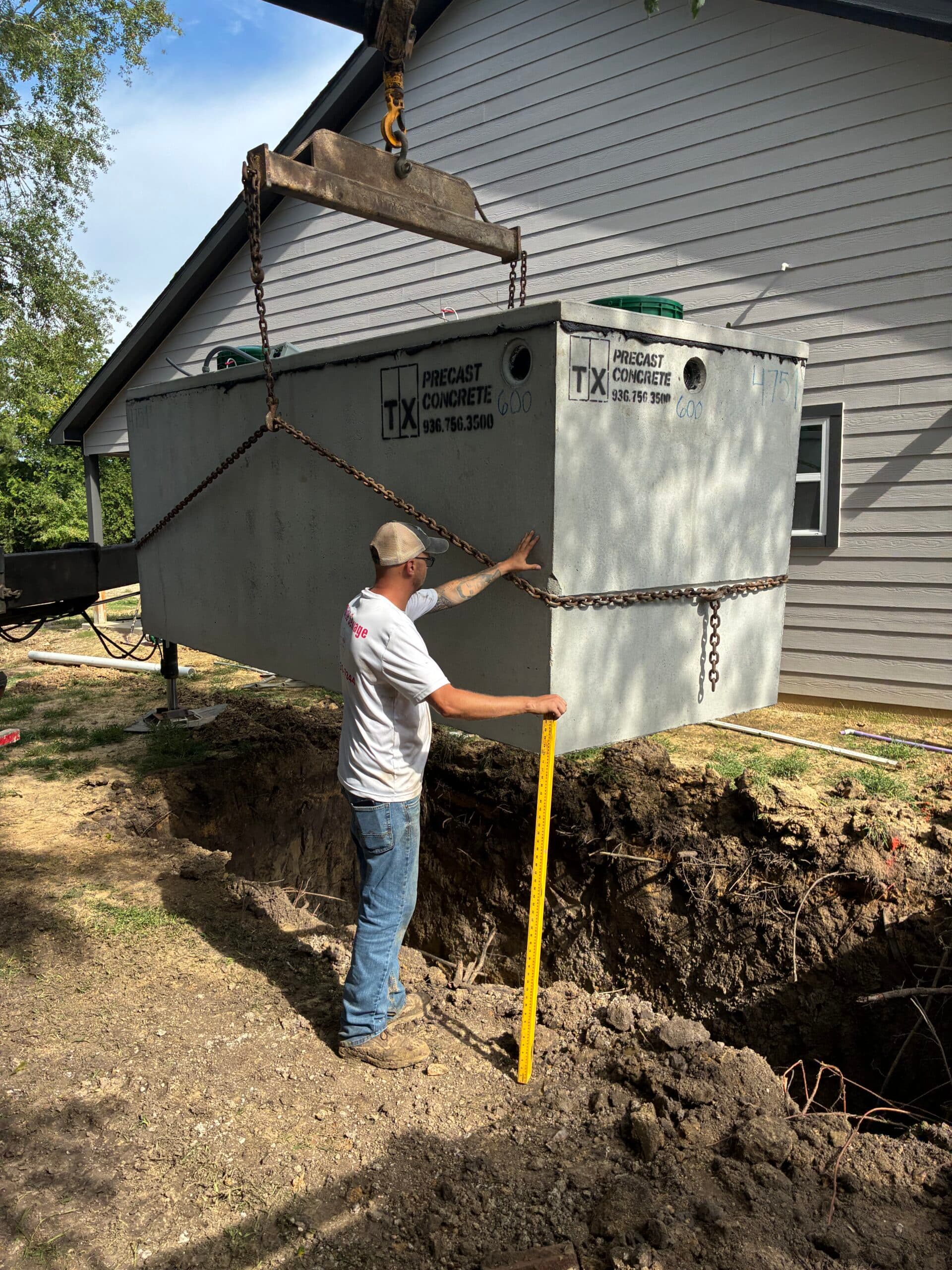 A concrete septic tank being set into a prepared excavation